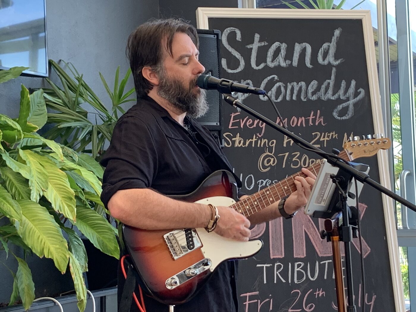 AJ Patrick playing an electric guitar at a daytime performance